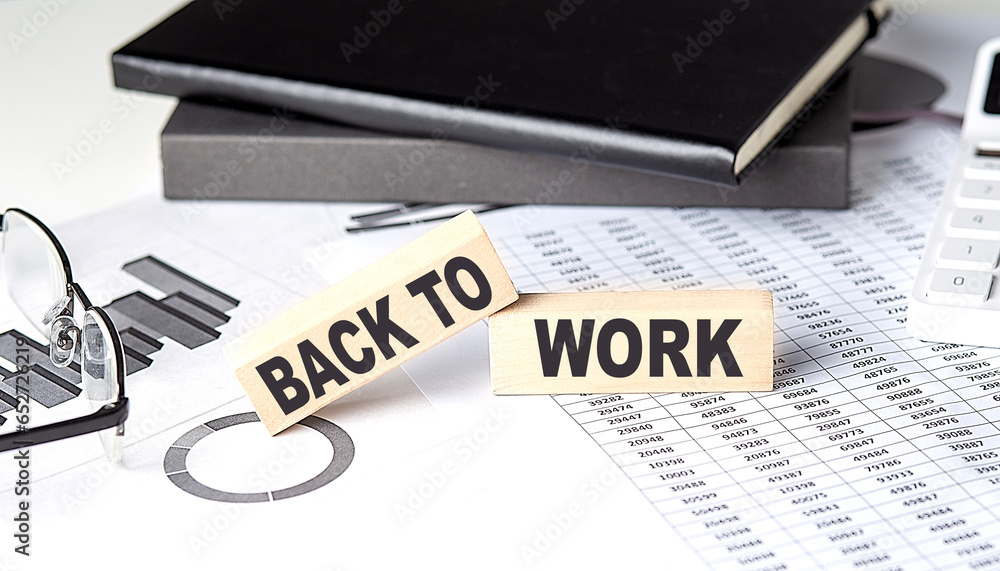 Aufkleber back to work - text on a wooden block with chart and notebook