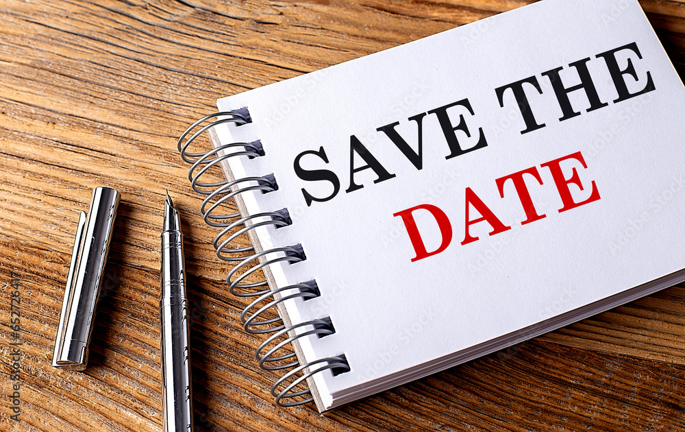 Poster save the date text on notebook with pen on wooden background