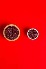Red kidney beans in a cup wooden isolated on red background