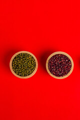 Mung beans and red kidney beans in a cup wooden isolated on red background