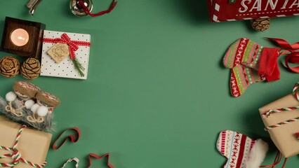 Colorful Christmas background 360 degree rotation shot on RED camera. Fir cones, red Santa mailbox, Christmas cookie cut out shapes, gift boxes in craft paper, candles spinning on green background 4K - Powered by Adobe