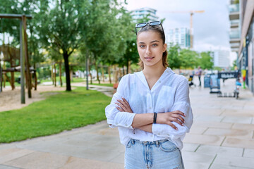 Fototapeta premium Portrait of teenage girl with crossed arms on street of city