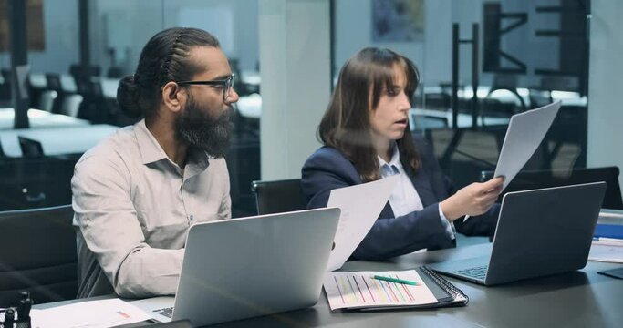 Diversity enriches the office as a capable Caucasian woman and a diligent Indian man come together to contribute their talents. Side by side, they navigate their tasks.