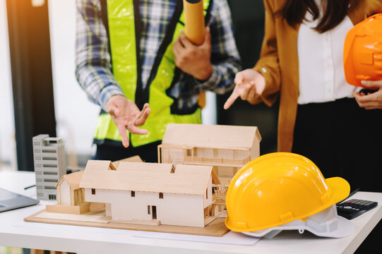 Two colleagues discussing data working and tablet, laptop with on architectural project at construction site at desk in modern office