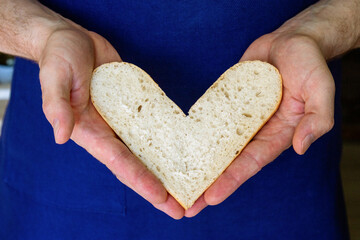 Bread folded in the shape of a heart, in male hands. The baker holds bread. Love for your work.