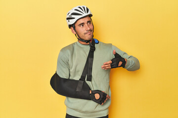 Injured cyclist with bike bag and arm brace on yellow.