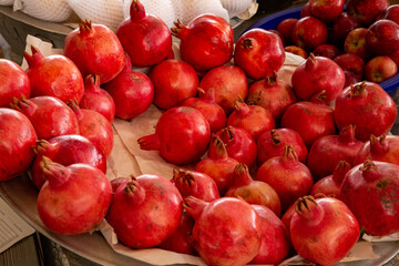 Pomegranates are piled on a plate in front of the shop for sale