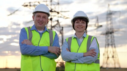 Happy electricians team with crossed arms stands by electric power substation