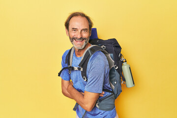 Fototapeta na wymiar Middle-aged hiker with backpack in studio laughing and having fun.