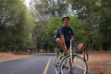 Man sitting on his bicycle taking a break at Prambanan temple, national park 5 September 2023