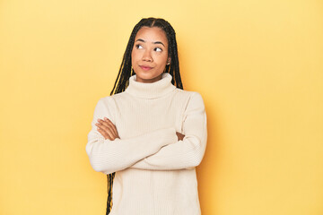 Young Indonesian woman on yellow studio backdrop dreaming of achieving goals and purposes