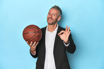 Middle-aged basketball coach on blue backdrop Middle-aged basketball coach on blue backdropcheerful...