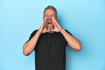 Middle-aged caucasian man on blue backdrop shouting excited to front.