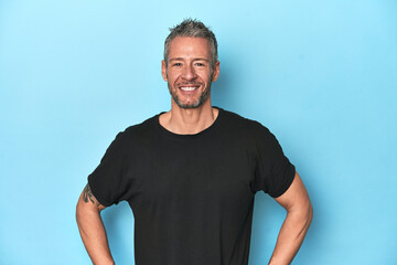 Obraz premium Middle-aged caucasian man on blue backdrop confident keeping hands on hips.