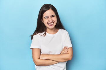 Young Caucasian woman on blue backdrop laughing and having fun.