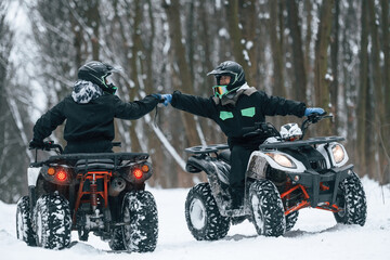 Preparing for the ride. Man and woman are on the ATV in the winter forest © standret