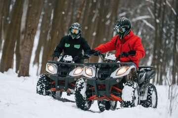 Conception of active recreation. Two people are riding ATV in the winter forest © standret