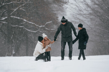 Front view. Happy family is outdoors, enjoying snow time at winter together