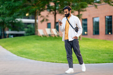 Full length of arabic guy with smartphone gadget texting outdoor