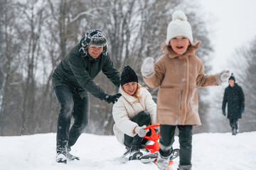 Woman is on sled ride. Happy family is outdoors, enjoying snow time at winter together