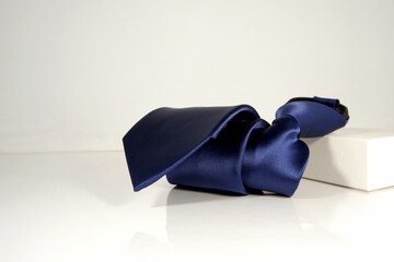 Closeup shot of a blue polyester fabric necktie rolled over on white background