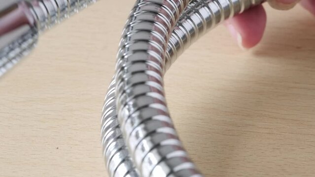 close-up of new metal stainless steel shower hose with double linkage, anti-twist, concept hygienic shower, locksmith work
