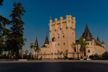 Obraz premium Young female posing at the historic Alcazar Castle against a clear sky, Segovia, Spain