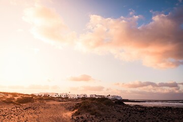 a sandy beach with small dunes and palm trees on a cloudy day