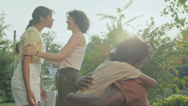 African American boy and girl greeting their relatives with hugs at party in backyard on summer day