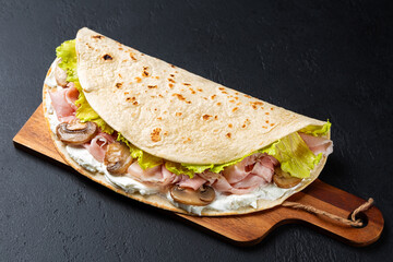 Traditional italian wrap or open sandwich on a wooden board. Piadina romagnola. Fatbread with...
