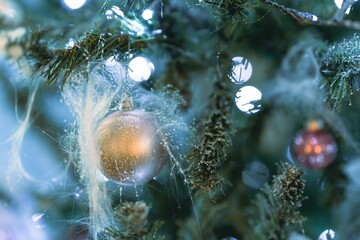 Golden Christmas decoration on a fir tree against bokeh lights