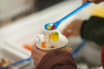 View of hands holding up a bowl filled with jelly and gummy bears