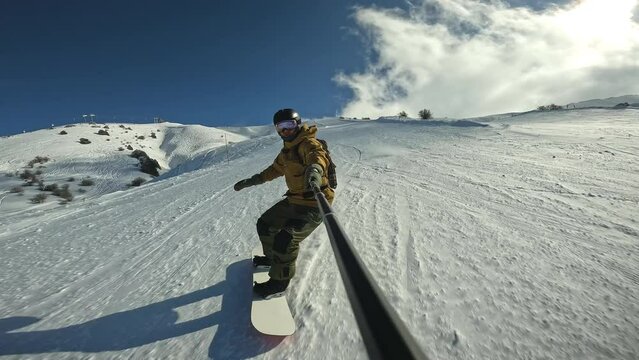 Snowboarder rides through snow and turns in fresh powder Snow splashes into athlete in wave Snowboarder wearing protective suit and goggles with helmet designed to protect snowboarder snow and falling