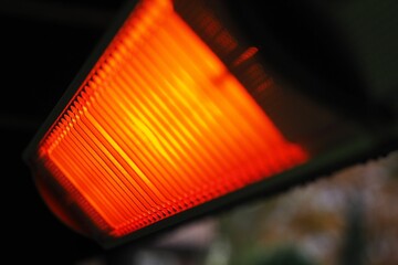 Vibrant orange heater is radiating heat on a wooden table
