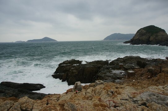 Scenic view of a rocky beach against sea waves on a cloudy day