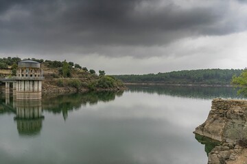 Naklejka premium El Villar reservoir in the mountains of Madrid on a day with overcast skies and clouds