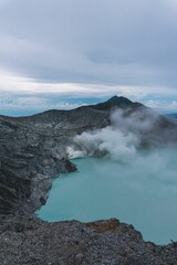 Vertical aerial view of a blue acid lake with sulfur steam near Mount Ijen, Java, Indonesia