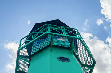 Small green lighthouse, view from bottom to top from close distance. Selective focus.