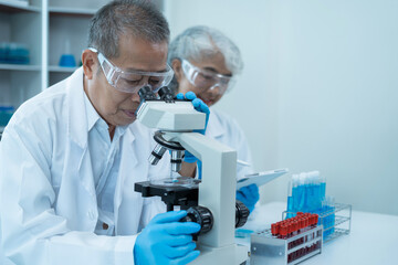 Team of biochemical research scientists working with a microscope for vaccine development in...