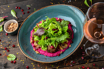 Warm eggplant salad on a bed of beets. Menu for a restaurant. Beautiful composition on wooden boards.