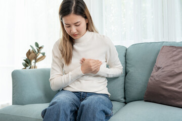 Obraz premium hand hold chest with heart attack symptoms, asian woman working hard have chest pain caused by heart disease, leak, dilatation, enlarged coronary heart, press on the chest with painful expression