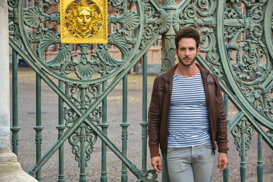 A man standing in front of a green gate in Piazza Castello in Turin, Italy