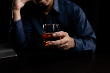 A man drinks whiskey, a businessman relieves stress from work sitting and drinking whiskey in the office after finishing a hard job, a drunk man. Alcohol drinking concept.