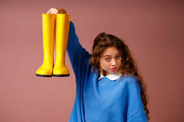 Young positive smiling woman holds in her hands a rubber boots