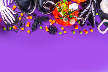 Bright colorful Halloween kids party accessories background, treat or trick holiday with colorful candies, traditional Halloween characters costumes, sweets, candy and decor top view copy space