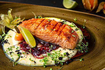 Grilled salmon on a vegetable pillow with berry sauce. Menu for a restaurant. Beautiful composition on wooden boards.