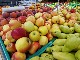 Apples and pears in plastic boxes in a store, close-up. Ripe apples for sale, side view. Selling fruits