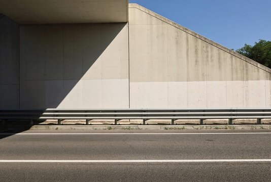 Guardrail in protection of sidewalk and concrete wall of an underpass . Two lane road in front. Background for copy space