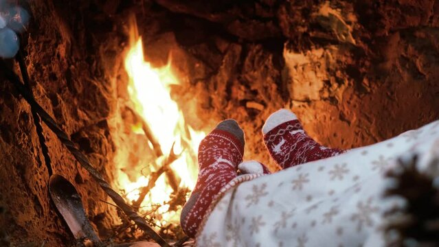 Couple of red christmas decorated socks heating in front of a fireplace with woods in xmas holidays season. Concept of people celebrating with romance and love. Man and woman enjoy chalet
