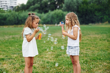 Obraz premium Bunch of bubbles. Two girls are playing together on the green field